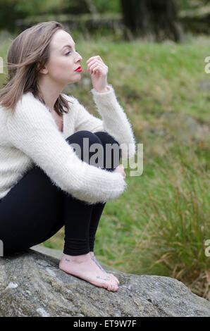 Jeune femme s'assit sur les rochers Banque D'Images