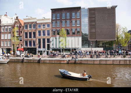 Petit bateau en canal et beaucoup de touristes en face de la maison d'Anne Frank à Amsterdam canal in spring Banque D'Images