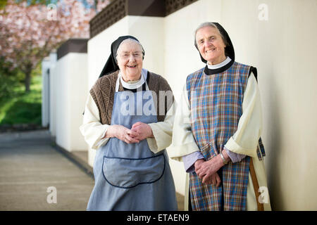 Deux moniales cisterciennes portant des tabliers de travail à l'abbaye Sainte Croix près de Whitland, Pembrokeshire Wales, UK Banque D'Images