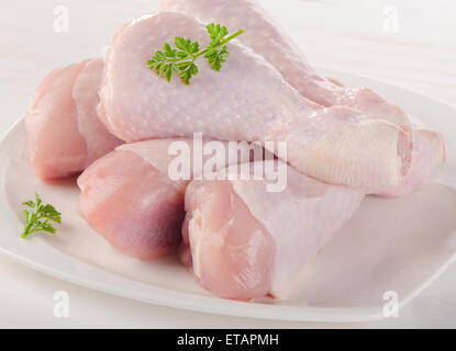 Cuisses de poulet frais sur plaque blanche. Banque D'Images