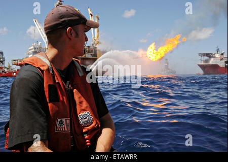 Un officier de la Garde côtière ne regarde la unité mobile de forage au large Q4000 pour contrôler le travail de la plateforme Deepwater Horizon endommagés comme les équipes travaillent pour boucher la sortie du puits et l'arrondi excès de gaz et pétrole du puits 8 juillet 2010 dans le golfe du Mexique. Banque D'Images