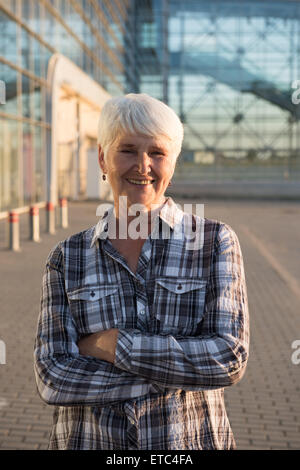 Personnes âgées senior woman standing in front of business building and smiling Banque D'Images