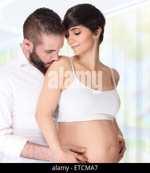 Portrait de couple d'amoureux à la maison, bel homme avec tendresse s'embrasser sa belle femme enceinte, profitant de la grossesse Banque D'Images