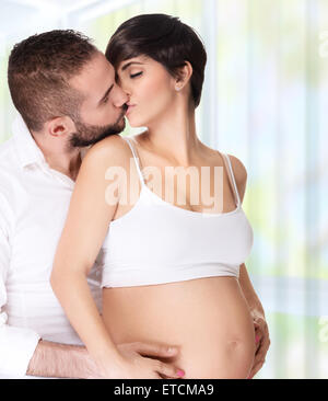 Portrait de couple d'amoureux à la maison, bel homme avec tendresse baisers avec sa belle femme enceinte, profitant de la grossesse Banque D'Images