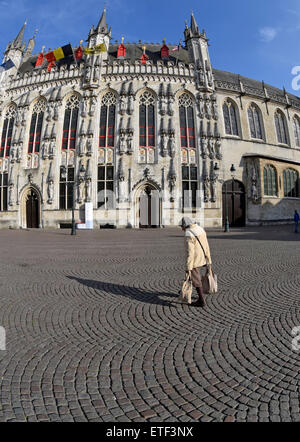 Une femme plus âgée avec les sacs en passant devant la mairie de place Burg, Bruges, Belgique Banque D'Images