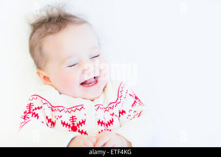 Cute funny baby girl laughing portant un chandail tricoté flocon Banque D'Images