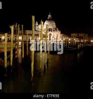 Pier de gondoles dans le Grand Canal, avec la Basilique de Santa Maria della Salute en arrière-plan à Venise, Italie, par nuit. Banque D'Images