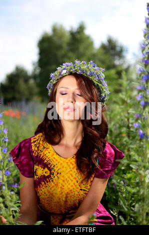 Belle fille de la Pologne avec couronne faite de fleurs. Portrait de modèle féminin entouré de bruyères. Banque D'Images