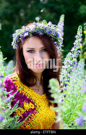 Belle fille de la Pologne avec couronne faite de fleurs. Portrait de modèle féminin entouré de bruyères. Banque D'Images