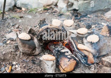 Cuisson des galettes sur des pierres chaudes par un incendie Banque D'Images