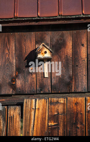 Format vertical d'une cabane en bois fixée à l'extérieur d'un vieux mur de la grange, a tanné. La fin de l'après-midi avec de grandes ombres. Banque D'Images