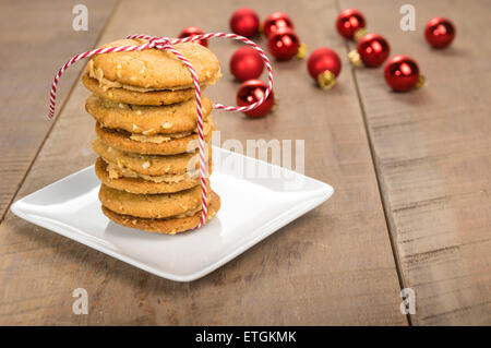 Une pile de beurre de cacahuète cookies faits maison remplie avec ornements rouge en arrière-plan Banque D'Images