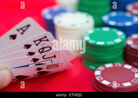 Poker player holding 10 à Ace spade quinte flush de poker à côté de beaucoup de jetons Banque D'Images