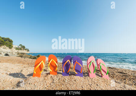 Tongs colorées de rangs à la plage Banque D'Images