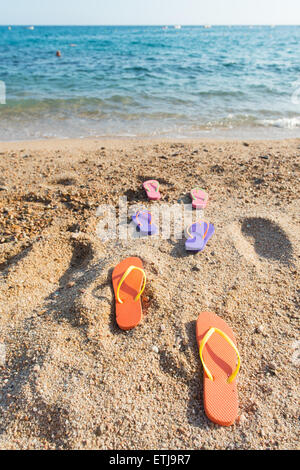 Tongs colorées de rangs à la plage Banque D'Images