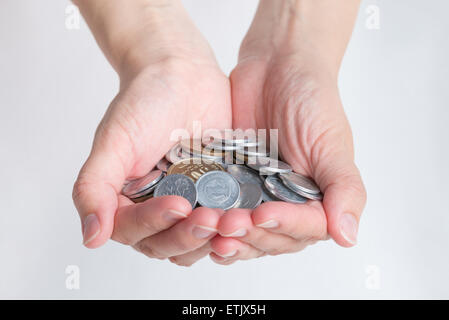 A woman's hands holding prit beaucoup de différentes pièces de monnaie Yen japonais avec un fond blanc. Banque D'Images