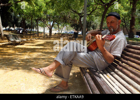 Man playing guitar on Park Bench (crédit image © Jack Ludlam) Banque D'Images