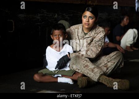 Un marine américain s'occupe d'un jeune réfugié l'Indonésie avant de transférer à un navire de la garde côtière indonésienne de l'USS Rushmore 11 juin 2015 dans l'océan Pacifique. L'équipage de la Rushmore au secours du groupe de réfugiés coincés entre les îles indonésiennes de Kalimantan et Sulawesi. Banque D'Images