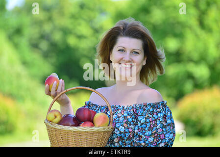 Une femme adulte avec un panier de fruits dans le parc Banque D'Images