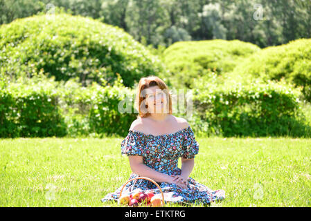 Une femme adulte avec un panier de fruits dans le parc Banque D'Images