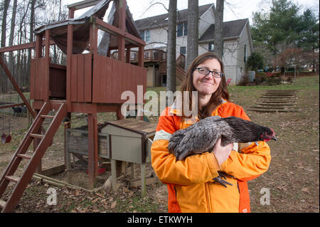 Femme tenant une poule dans la cour arrière près d'un poulailler à Eldersburg, Maryland, USA Banque D'Images