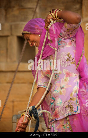 Femme du Rajasthan la collecte de l'eau d'un puits à Amar Sagar, Lodurva nr, Jaisalmer, Rajasthan, India Banque D'Images