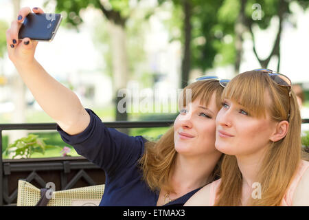 Deux jumeaux filles prenant en selfies restaurant au jour d'été ensoleillé. Young pretty sisters sur terrasse du café Banque D'Images
