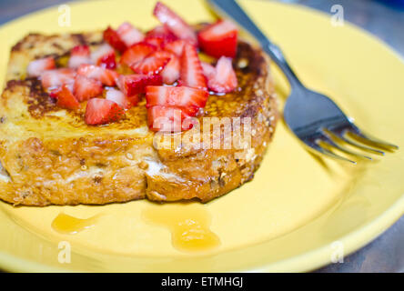 Pain doré farci au fromage, crème de fraise, et le sommet, avec des morceaux de fraises et de sirop d'érable. Le petit-déjeuner sur une assiette. Banque D'Images