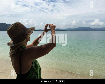 Femme sur la plage de la prise d'une photo Banque D'Images