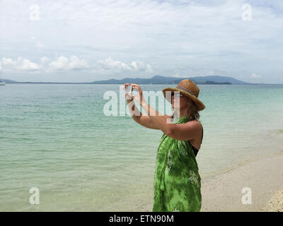 Femme debout sur la plage prenant une photo, Phuket, Thaïlande Banque D'Images