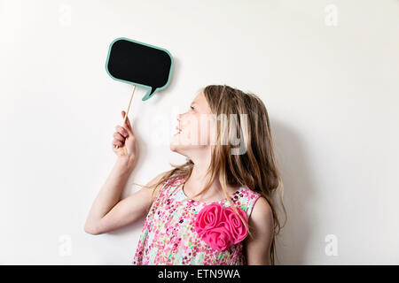 Portrait of a happy girl holding a blank bulle pensée bord au-dessus de sa tête Banque D'Images