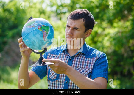 Homme de la rue, tenant un globe sur fond vert de l'été Banque D'Images