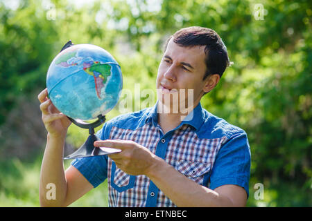 Homme de la rue, tenant un globe sur fond vert de l'été Banque D'Images