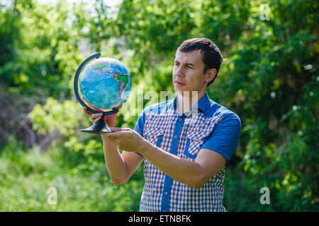 Homme de la rue, tenant un globe sur fond vert l'été Banque D'Images