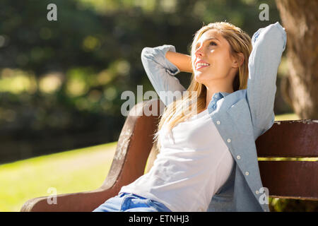 Happy young woman relaxing on a park bench Banque D'Images