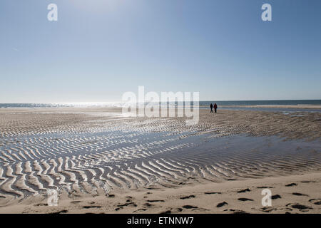 Plage à marée basse, deux personnes marchant sur le banc de sable Banque D'Images