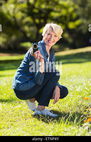 Cheerful senior woman holding a camera outdoors Banque D'Images