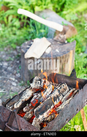Bois de chauffage à combustion vieux brazier avec ax dans une souche sur l'arrière-plan Banque D'Images