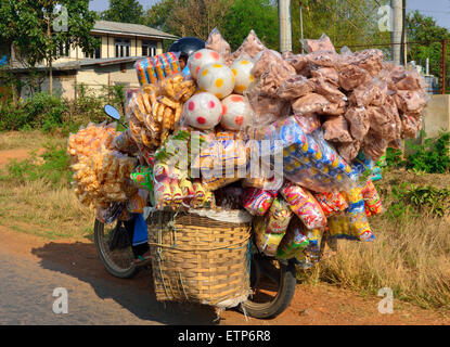 Un commerçant surchargé sur sa moto transportant ses marchandises au marché sur la route principale à Battenburg au Cambodge, en Asie du Sud-est Banque D'Images