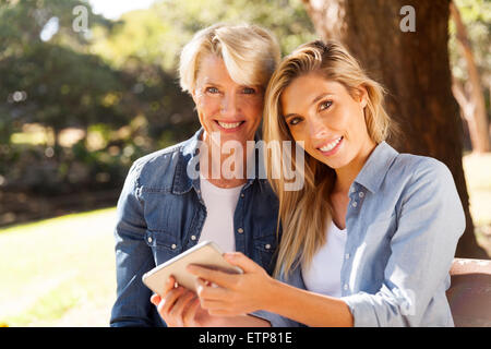 Portrait de jolie mère et fille à l'aide de smart phone dans le parc Banque D'Images