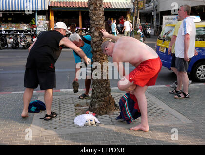 Les touristes masculins dépose le sable de leurs chaussures à Beach Road, à Pattaya en Thaïlande Banque D'Images