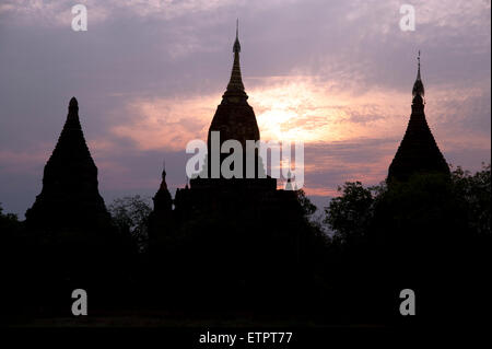 Trois silhouettes sombres des flèches contre le temple d'or d'un coucher de Bagan Myanmar Banque D'Images