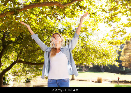 Happy young woman with arms open sous les arbres Banque D'Images