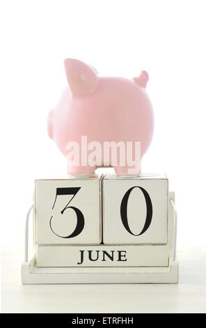 Fin de l'année financière Concept épargne avec tirelire en bois et calendrier sur table en bois blanc. Banque D'Images