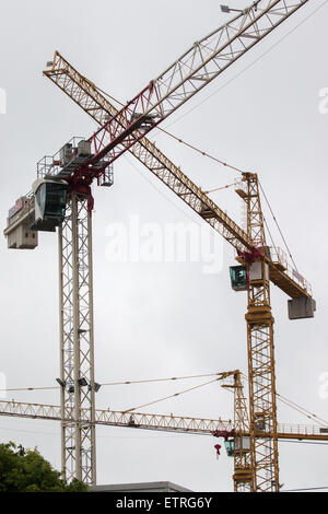 Plusieurs grues de construction construction jaune contre un ciel couvert. Banque D'Images