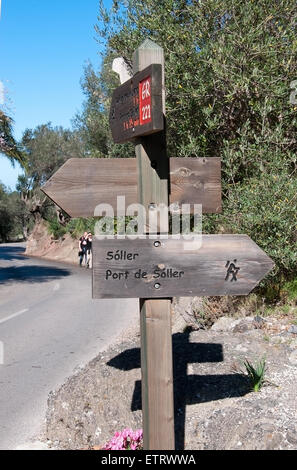 Par le panneau de bois route de pierres sèches et deux 221 marcheurs le 7 février 2013 à Puerto Alcudia, Mallorca, Espagne. Banque D'Images