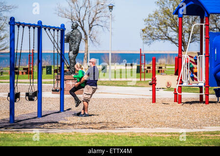 Un père de race blanche balançoires sa fille de 10 ans dans un jeu public à Oklahoma City, Oklahoma, USA. Banque D'Images