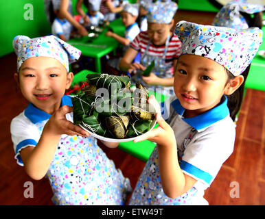 La Chine Handan, Province de Hebei. 16 Juin, 2015. Les enfants montrent Zongzi, une boulette de riz gluant enveloppé dans des feuilles de roseau ou de bambou, à l'occasion du prochain Festival du bateau-dragon dans la région de Urumqi, Chine du nord, dans la province du Hebei, le 16 juin 2015. Le Dragon Boat Festival, également connu sous le nom de Duanwu, est célébrée chaque année le cinquième jour du cinquième mois du calendrier lunaire chinois, qui tombe le 20 juin cette année. © Qinghua Hu/Xinhua/Alamy Live News Banque D'Images