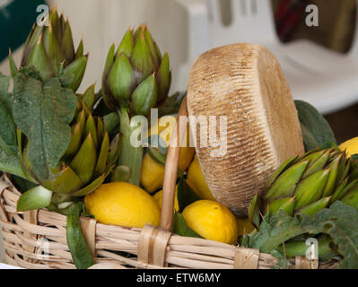 Panier en osier avec du fromage, les citrons et les artichauts Banque D'Images