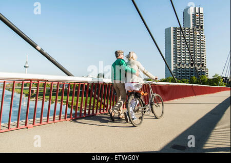 Allemagne, Mannheim, couple d'âge mûr crossing bridge, poussant location Banque D'Images